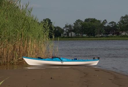 Kayak on a beach at low tide with marsh grass.