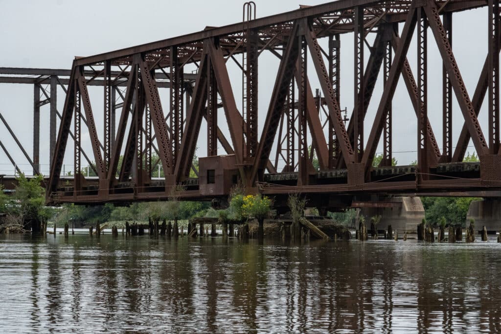 A disused railroad swing bridge balanced in the center of the Christina River.